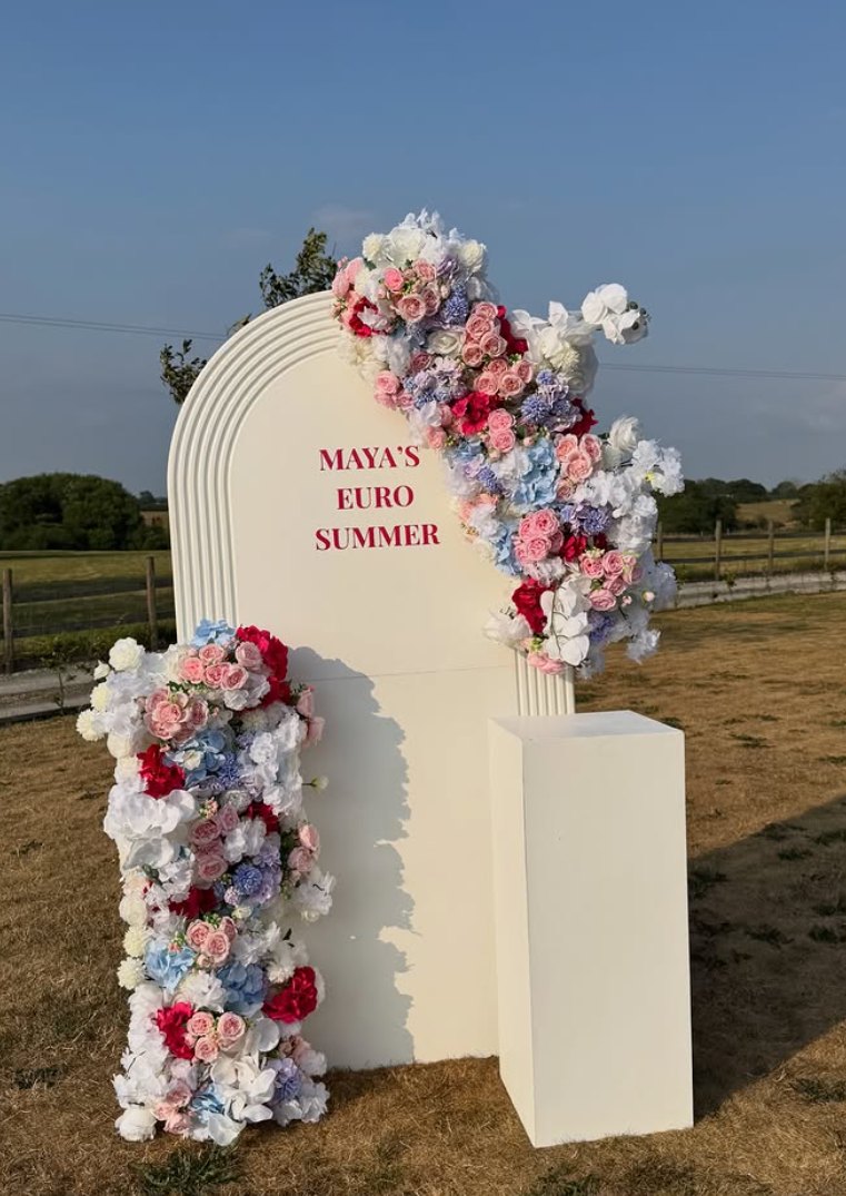 Cream arch board dressed with pink, blue and white florals set up outdoors